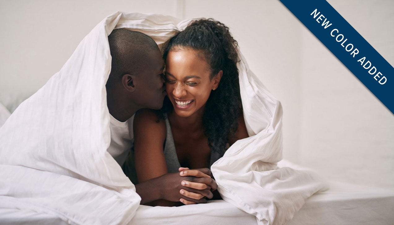 smiling couple laying under the covers