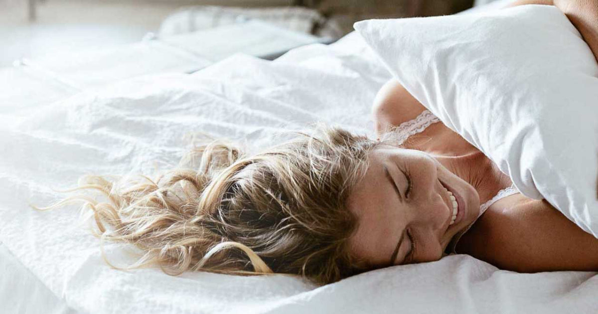 photo of a woman laying in bed smilng holding her pillow