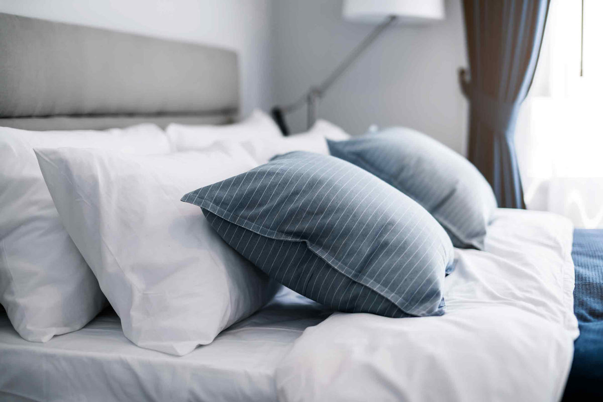 Photo of a newly made bed with 6 pillows neatly laid out