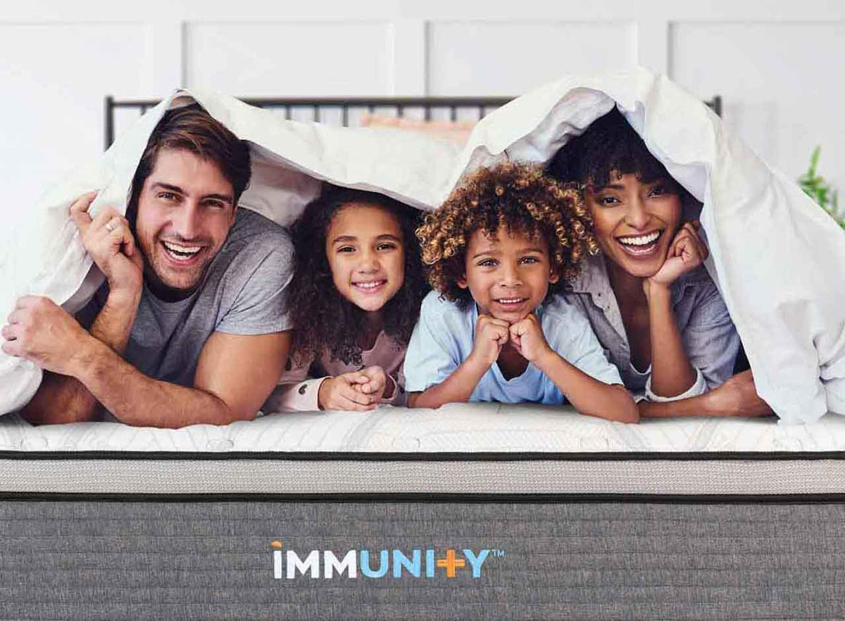 Family laying on their new immunity mattress smiling under the covers